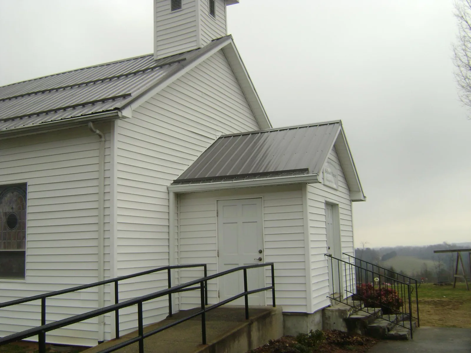 Gray metal roof on a white clapboard church with a steeple in Salem