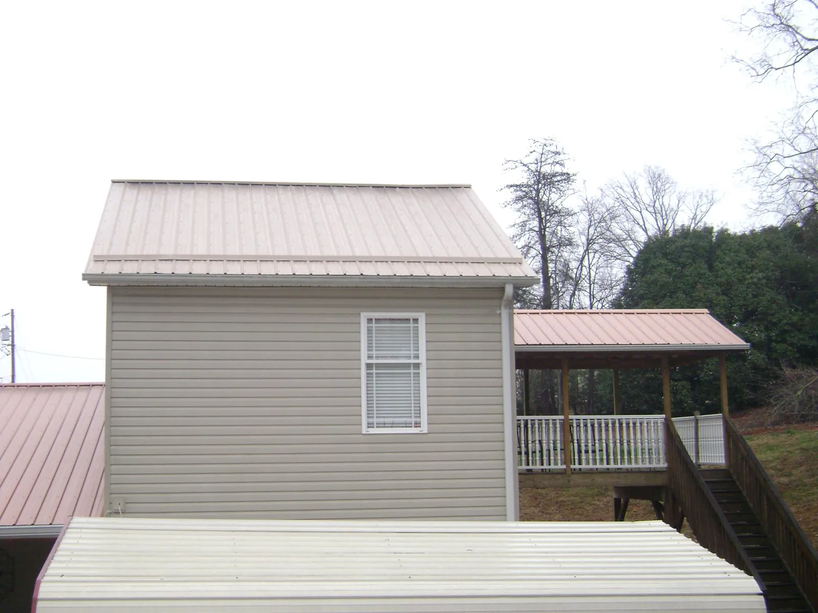 Tan metal roofs on a two story addition and attached porch, from a Roof Replacement job in Salem
