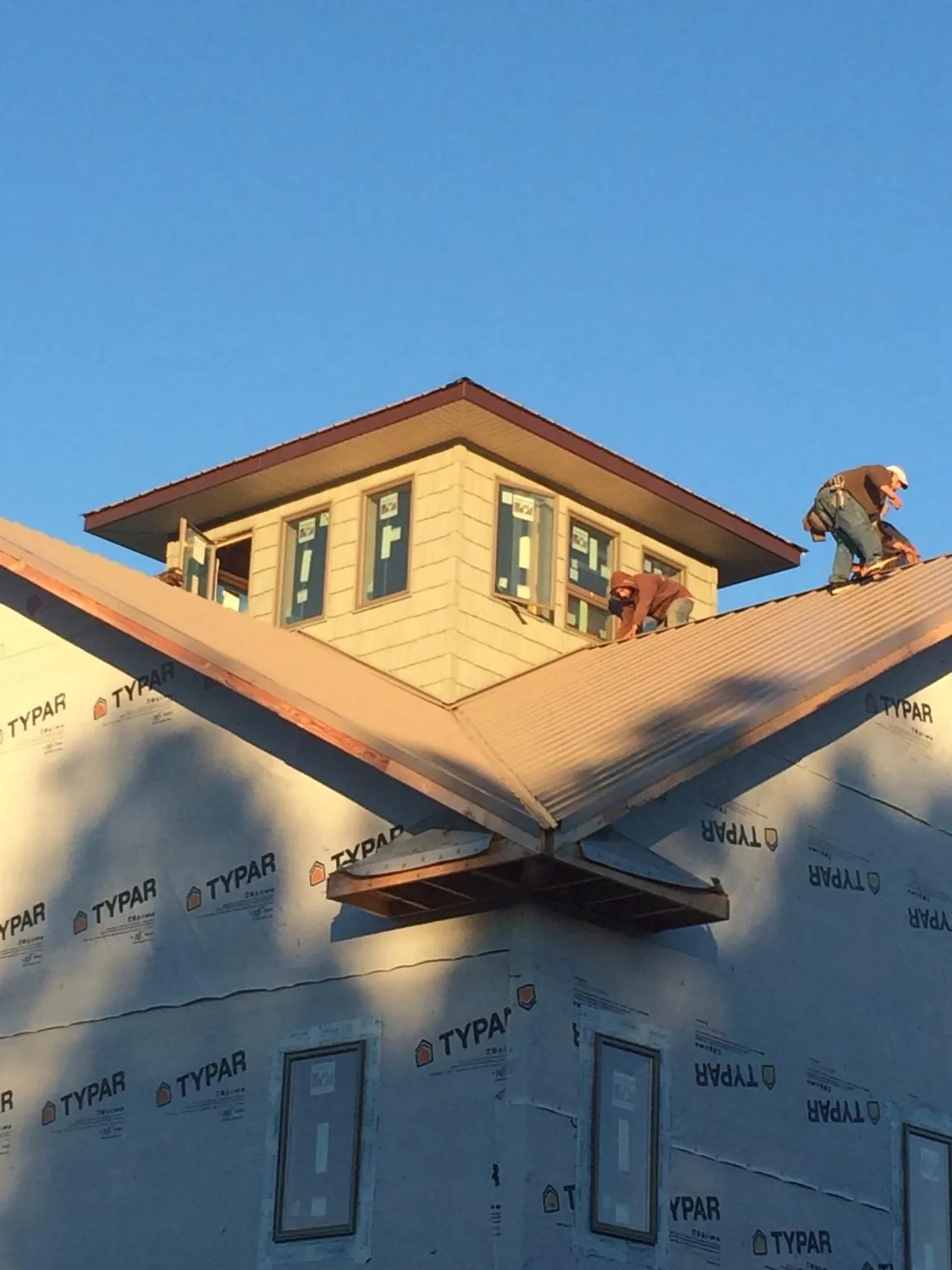 Roofers working around a rooftop cupola on a new metal roof at sunset — Roof Waterproofing in Salem by Roofing Brothers